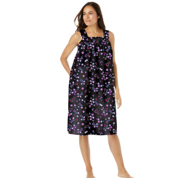 Plus-size woman wearing a sleeveless, mid-length lounger with a black floral print, featuring a square neckline, shirred yoke, and side pockets.