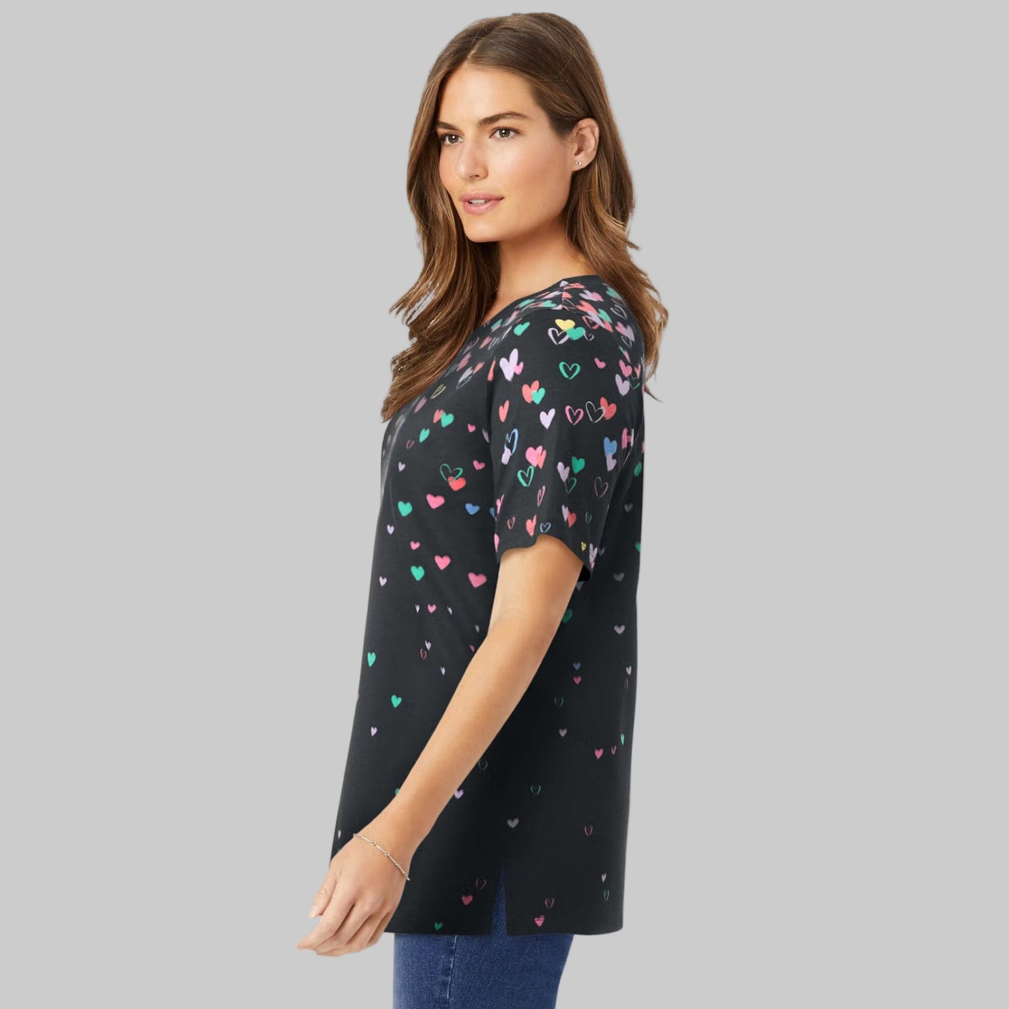 Women’s black graphic tee with colorful falling heart print, short sleeves, and relaxed fit, displayed on a clean studio background.