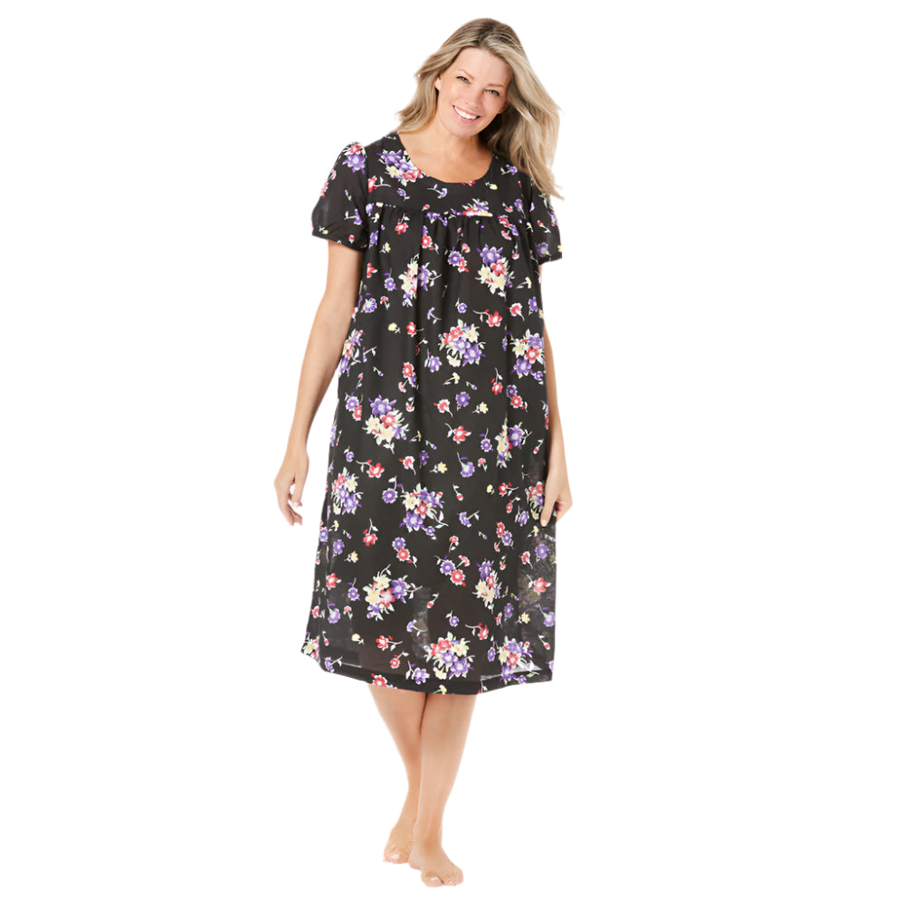 Plus-size short-sleeve lounger in black with tossed floral print, featuring shirred front and back yokes, side pockets, and 44-inch length.