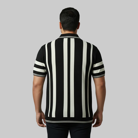 Black and white vertical stripe polo t-shirt worn by a male model, featuring a classic collar and short sleeves on a clean studio background