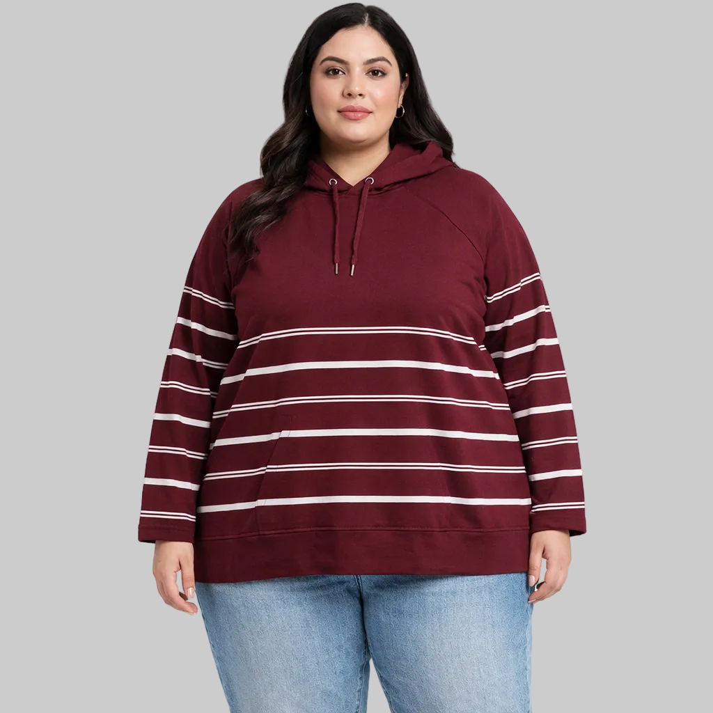 Plus size women wearing burgundy bell sleeve French terry sweatshirt with striped sleeves paired with light blue jeans.