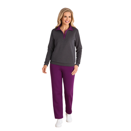 Plus size woman wearing a charcoal zip-front fleece pullover with purple collar and matching purple lounge pants, standing indoors in a relaxed pose.