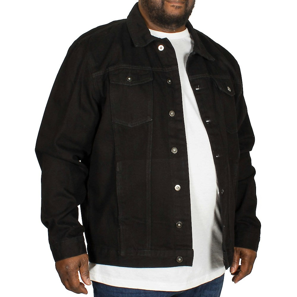 Plus-size male model wearing a classic black denim jacket with button-down front, straight collar, and chest flap pockets, photographed in a studio on a white background
