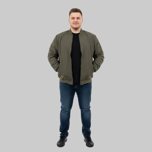 Plus-size male model wearing a classic olive bomber jacket with ribbed cuffs, collar, and hem – front view, hands in pockets.