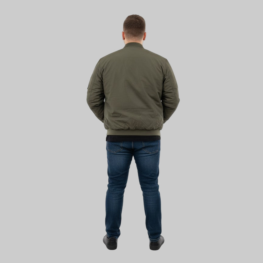 Plus-size male model wearing a classic olive bomber jacket with ribbed cuffs, collar, and hem – front view, hands in pockets.