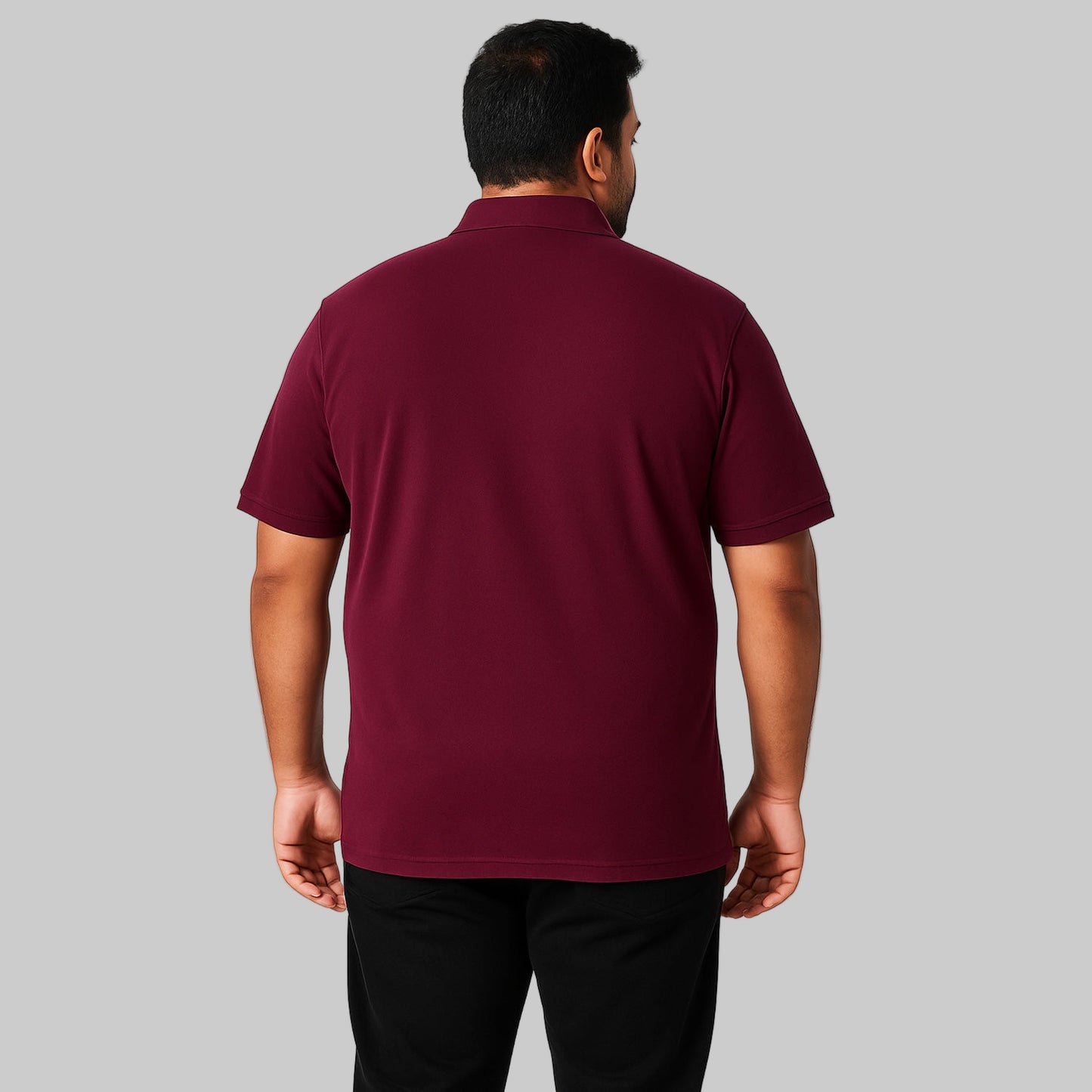 Plus-size Pakistani male model wearing dark magenta piqué polo shirt with chest pocket on a clean studio background.