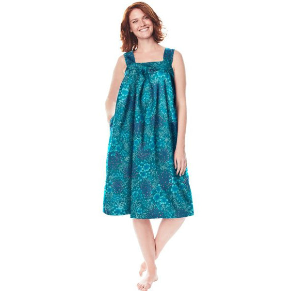 Plus-size woman wearing a sleeveless, mid-length lounger with a deep teal painted floral print, featuring a square neckline, shirred yoke, and side pockets.