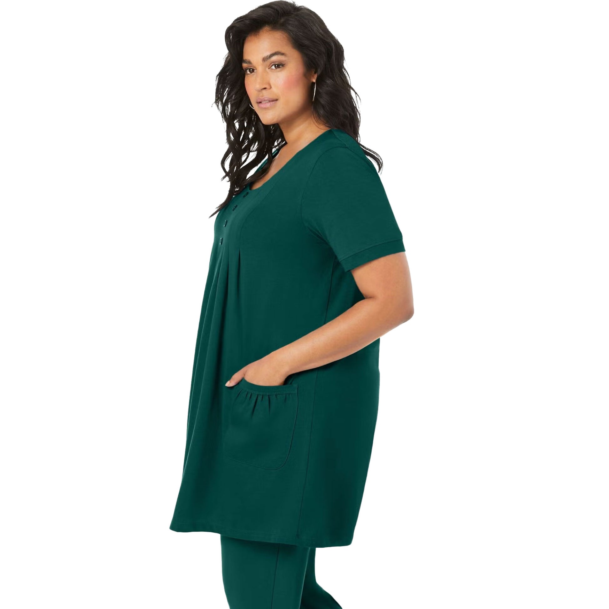 Emerald green knit women’s tunic with two front pockets, draped on a hanger with a white background