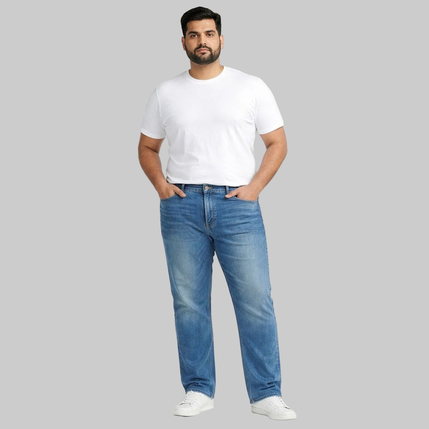 Pakistani male model wearing size 2XL mid blue comfort straight leg denim jeans with a plain white t-shirt, full body studio shot on a clean white background.