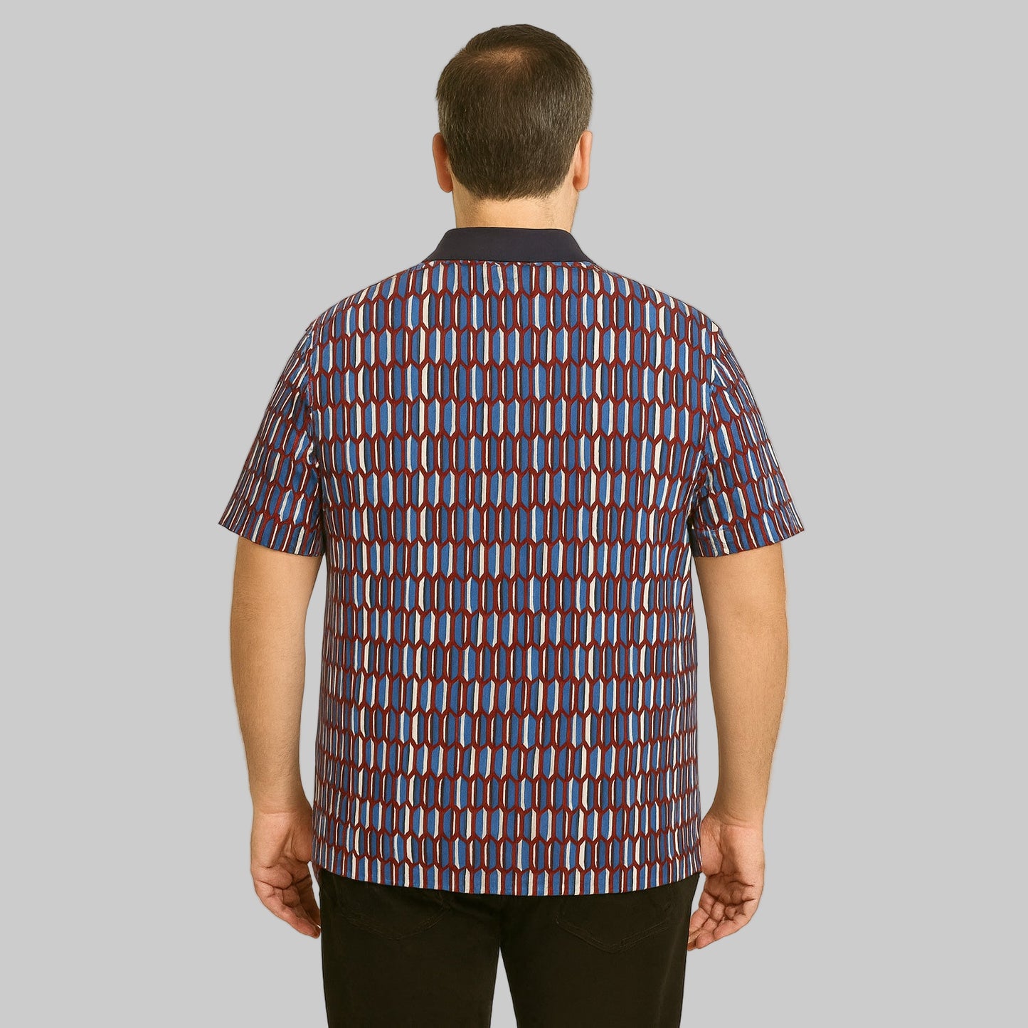 Plus-size Pakistani male model wearing navy geo colorblock quarter-zip polo shirt with ribbed collar on a clean studio background.