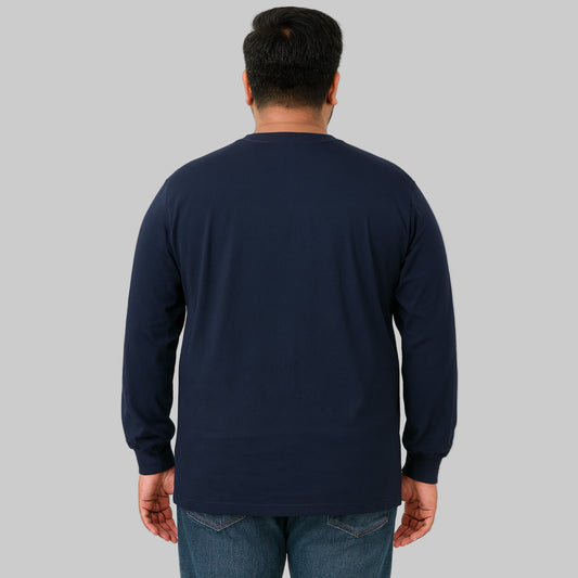 Plus-size male model wearing navy long sleeve pocket T-shirt, relaxed fit, front view, studio background.