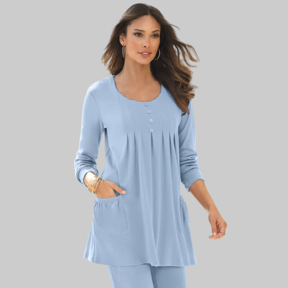 Plus-size woman wearing a pale blue long sleeve soft knit swing tunic with two pockets and pleated front, captured in a clean studio background.