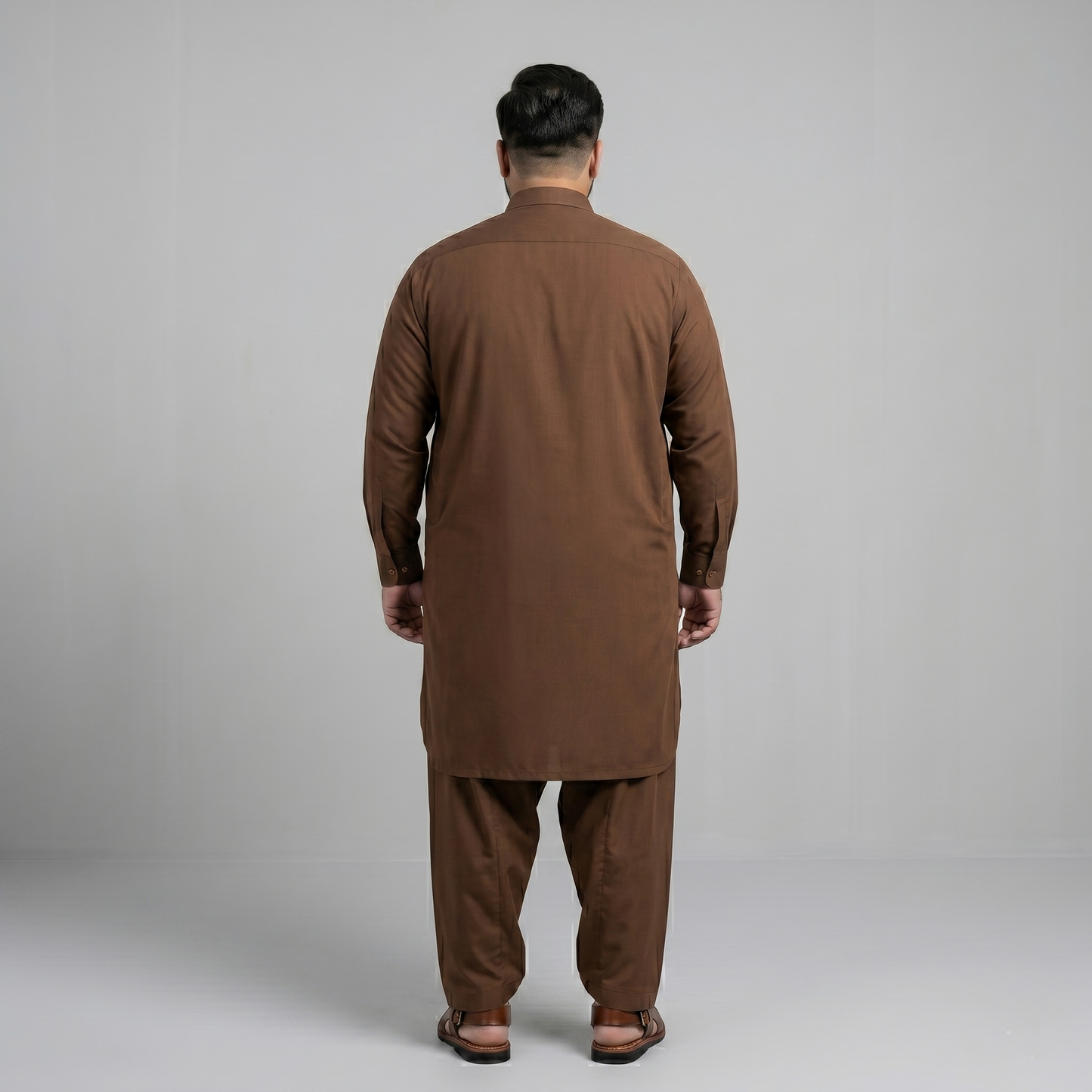 Man wearing a brown traditional outfit against a gray background