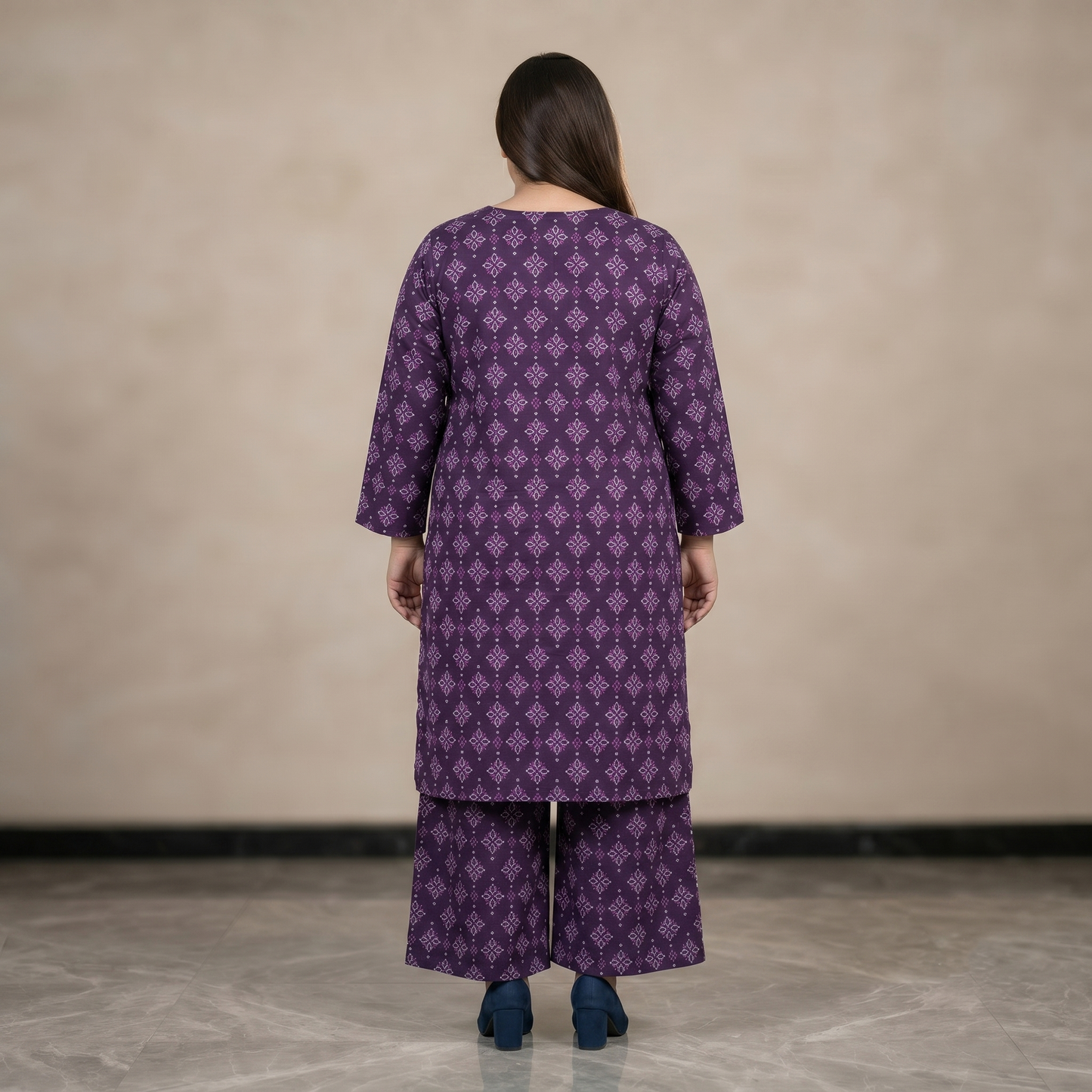 Women wearing a purple patterned outfit standing against a plain background