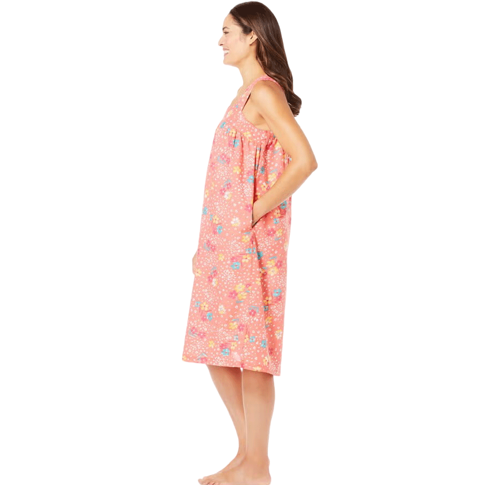 Plus-size woman wearing a sleeveless, mid-length lounger with a sweet coral floral print, featuring a square neckline, shirred yoke, and side pockets.