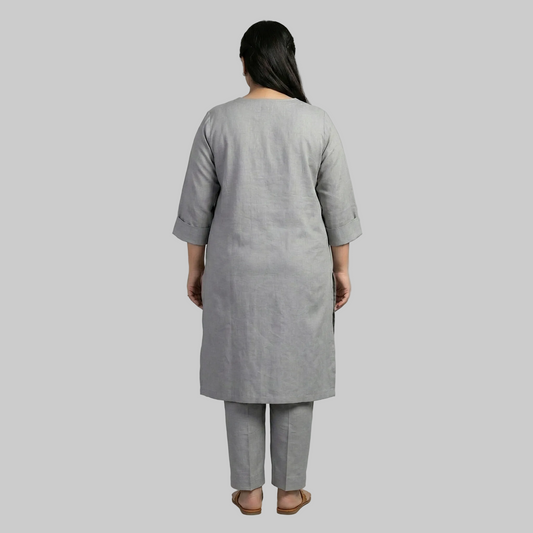 Person wearing a gray kurta with pants on a gray background