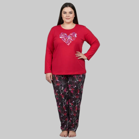 Plus-size woman wearing a red long-sleeve heart print cotton pajama set with black printed trousers on a gray background.