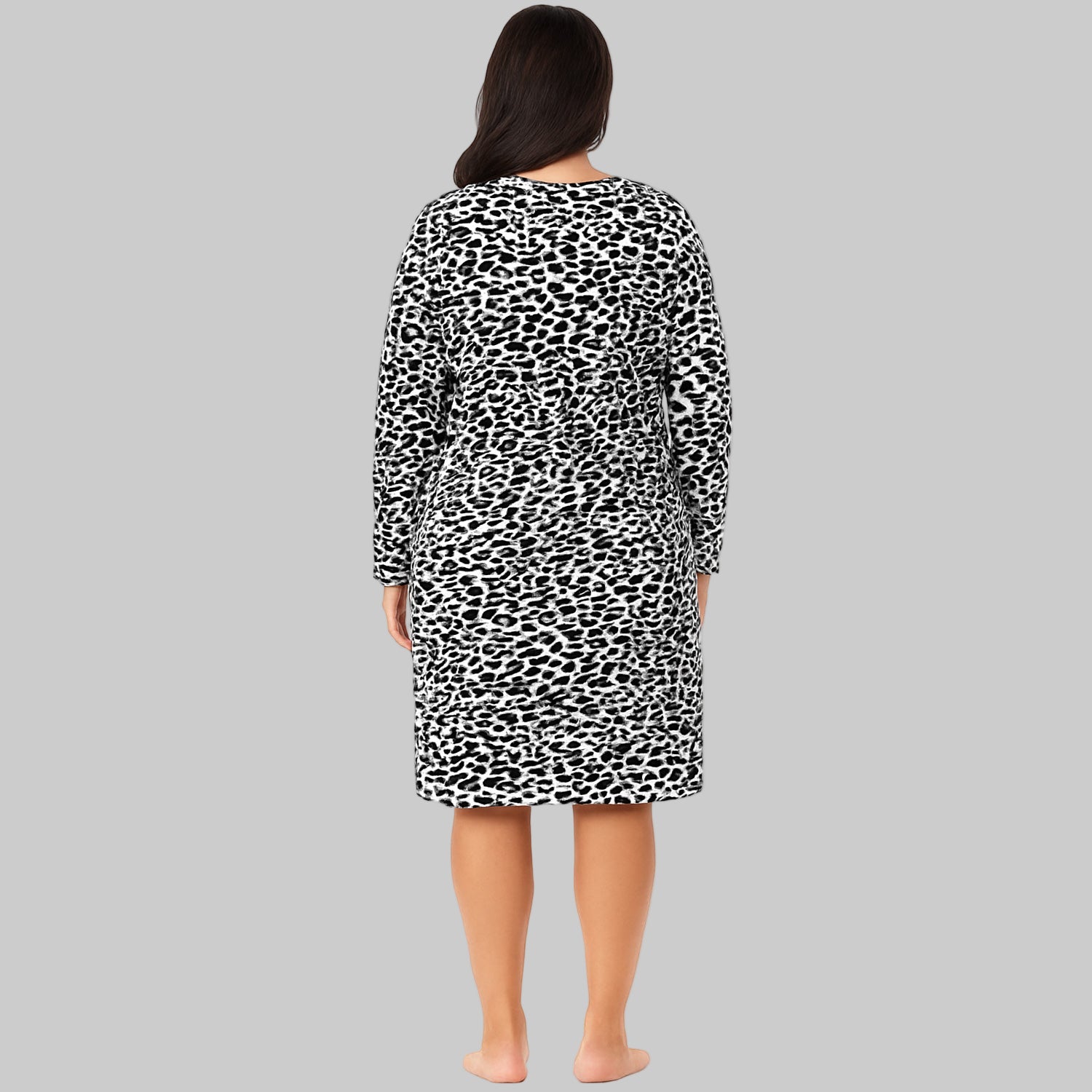 Plus-size woman wearing a black abstract printed long-sleeve cotton sleepshirt, standing barefoot on a white background.
