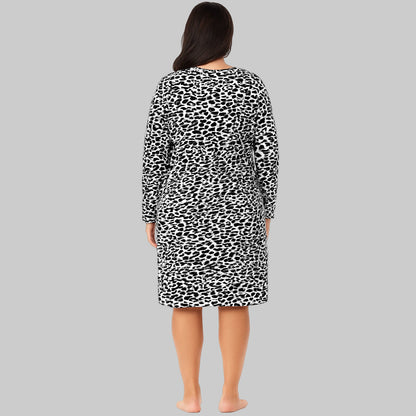 Plus-size woman wearing a black abstract printed long-sleeve cotton sleepshirt, standing barefoot on a white background.