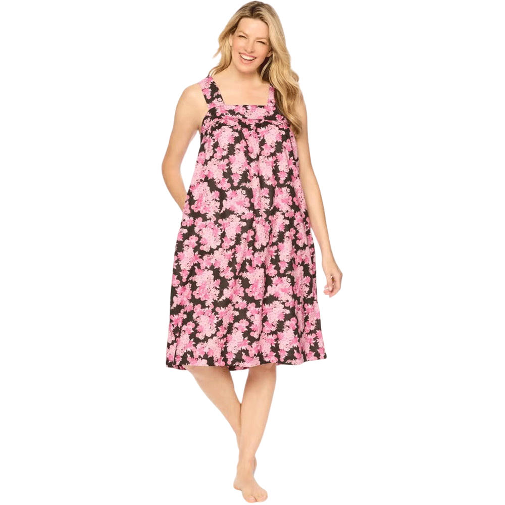 Plus-size woman wearing a sleeveless, mid-length lounger with a black camellia floral print, featuring a square neckline, shirred yoke, and side pockets.​

