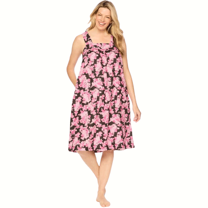 Plus-size woman wearing a sleeveless, mid-length lounger with a black camellia floral print, featuring a square neckline, shirred yoke, and side pockets.​

