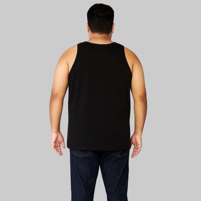 Plus-size Pakistani male model wearing a black sleeveless cotton tank top with dark jeans on a light-gray background, relaxed fit casual wear.