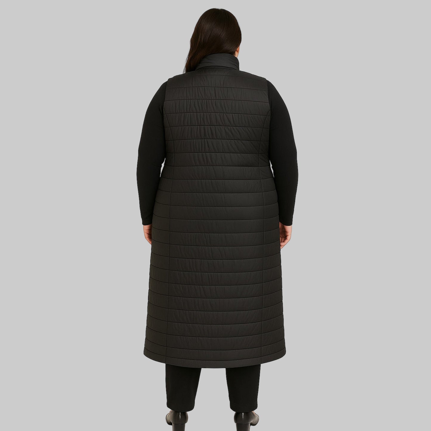 Plus-size female model wearing a long black quilted puffer sleeveless jacket with a zip-front closure, front view.