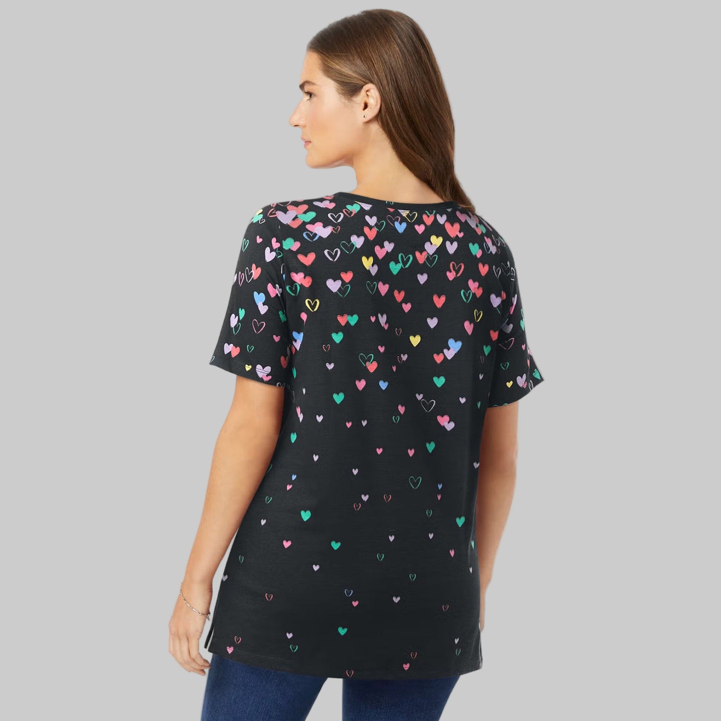 Women’s black graphic tee with colorful falling heart print, short sleeves, and relaxed fit, displayed on a clean studio background.