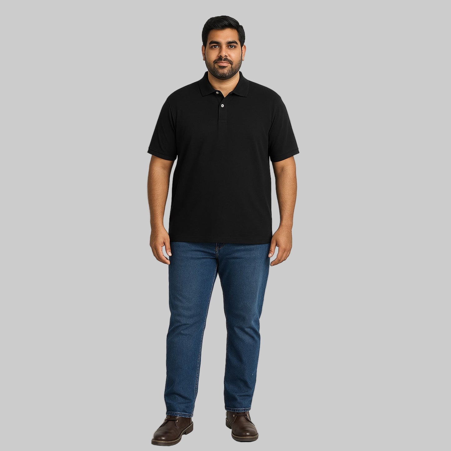 Plus-size Pakistani male model wearing black piqué polo shirt with dark jeans on a light studio background, relaxed fit.