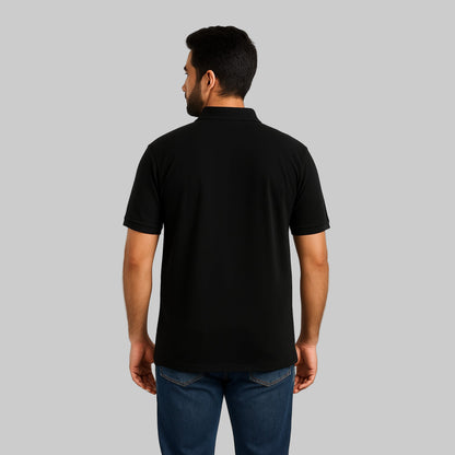 Plus-size Pakistani male model wearing black piqué polo shirt with dark jeans on a light studio background, relaxed fit.