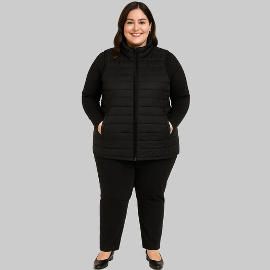Plus-size female model wearing a black short sleeveless quilted puffer jacket with a zip-front closure.