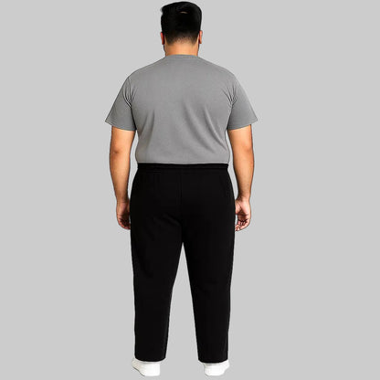 Black plus-size jogger trousers with subtle side stripe, worn by a 2XL Pakistani male model on a clean white background.