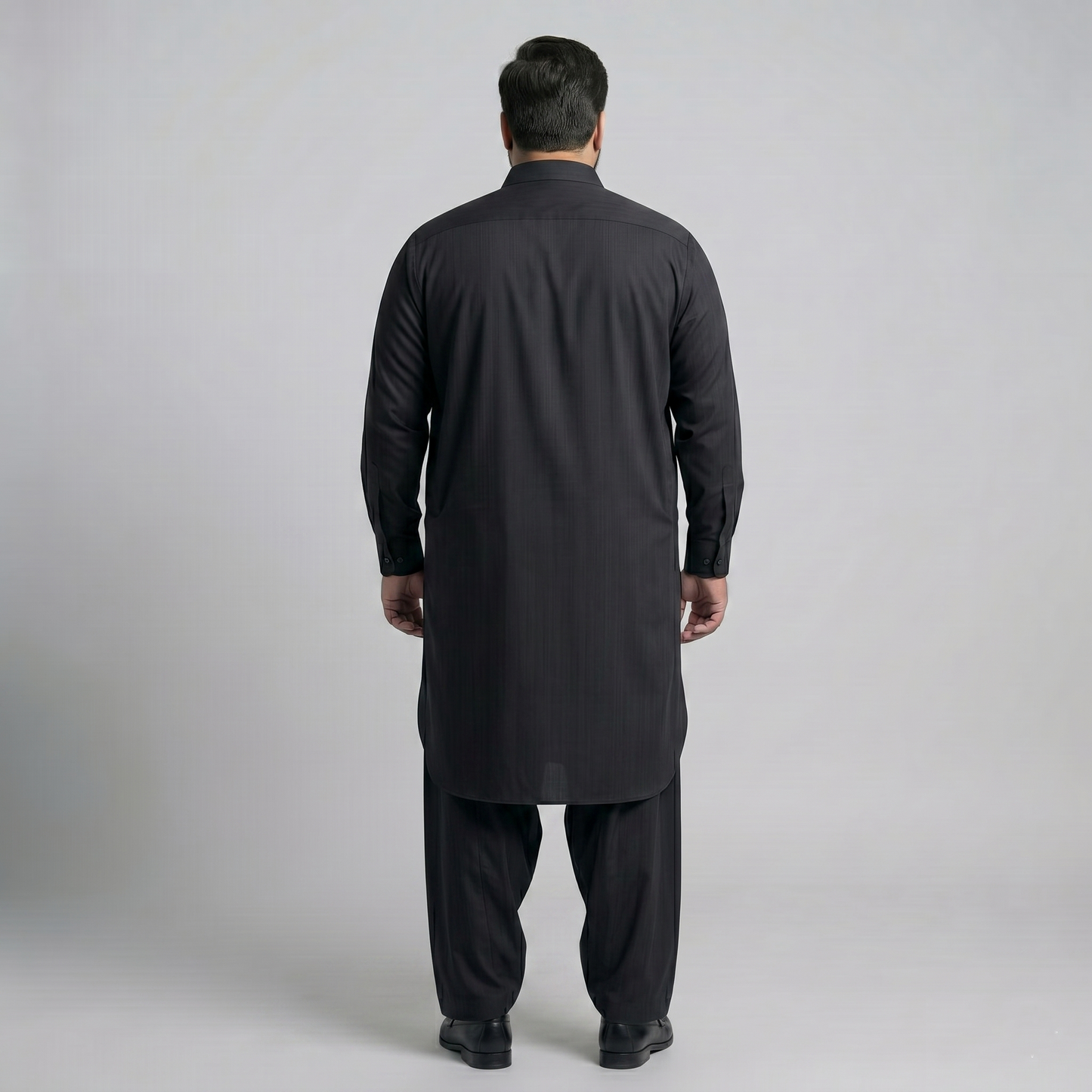 Man wearing a black kurta with pants on a light gray background