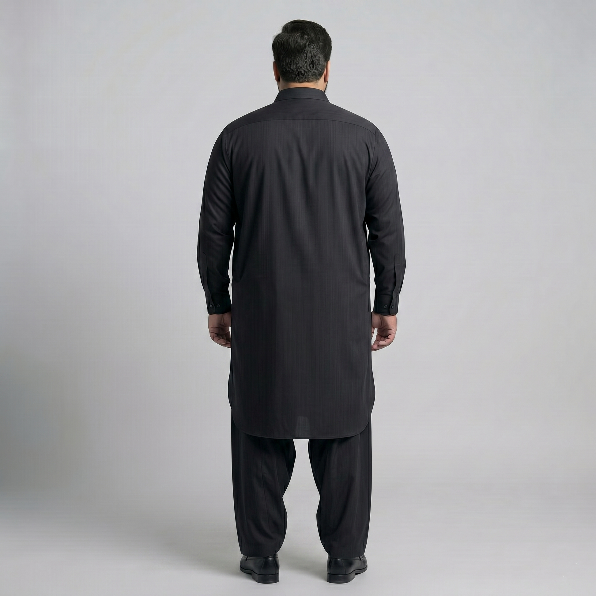 Man wearing a black kurta with pants on a light gray background