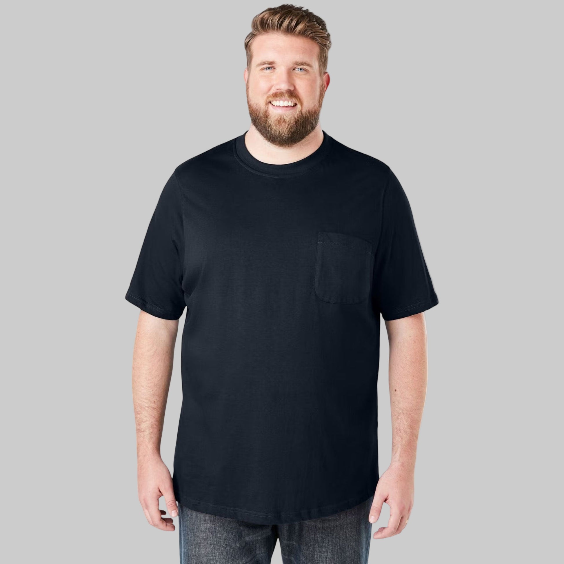 Plus-size Pakistani male model wearing black crewneck cotton T-shirt with pocket, front view on light-gray background, casual relaxed fit.