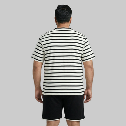 Man wearing a black and white striped shirt and black shorts on a gray background