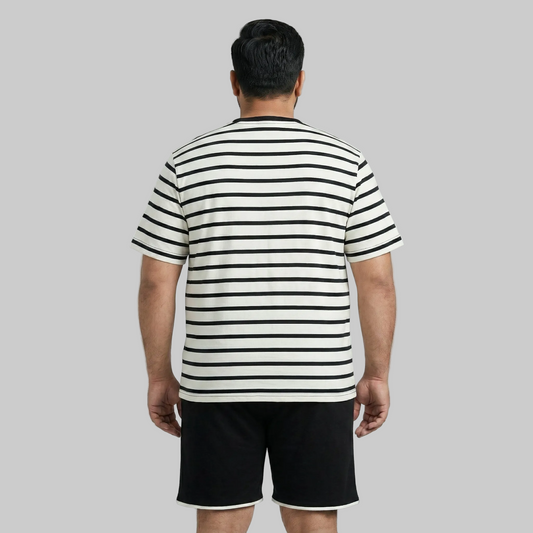 Man wearing a black and white striped shirt and black shorts on a gray background