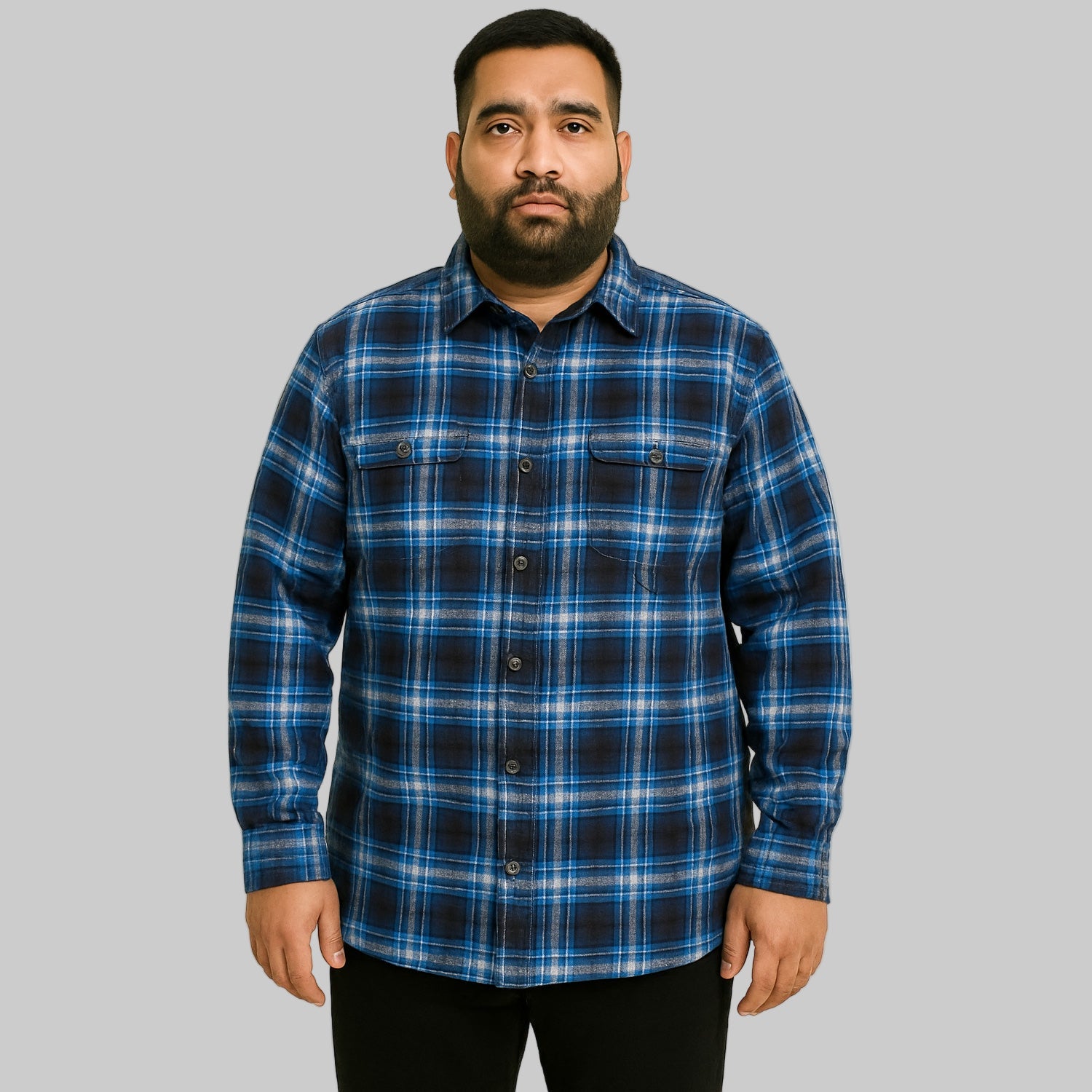 Plus-size Pakistani male model wearing blue check fleece-lined flannel shirt jacket on a light studio background, front and side pockets visible.