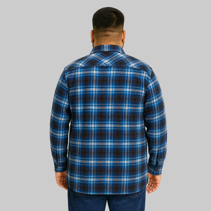 Plus-size Pakistani male model wearing blue check fleece-lined flannel shirt jacket on a light studio background, front and side pockets visible.