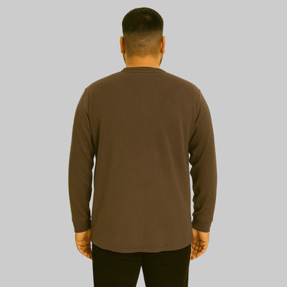 Plus-size Pakistani male model wearing brown waffle-knit thermal Henley tee on a studio background, long sleeves, relaxed fit.