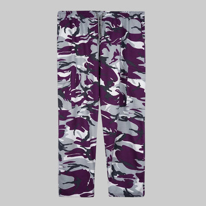 Camo Charge plus-size terry cargo pants worn by a Pakistani male model in a side pose, featuring a purple, grey, white, and black camouflage print with elastic waistband and side cargo pockets.