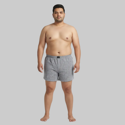 Black and white vertical stripe cotton boxer with elastic waistband and button fly laid flat on a white background