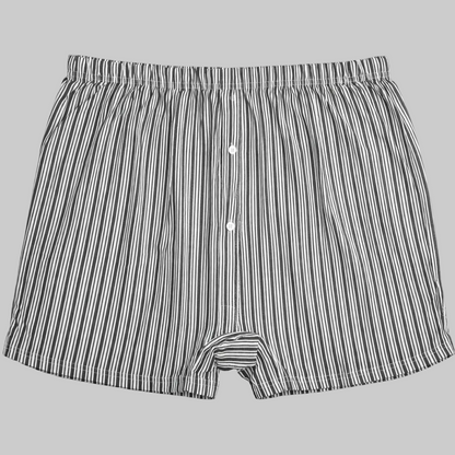 Black and white vertical stripe cotton boxer with elastic waistband and button fly laid flat on a white background