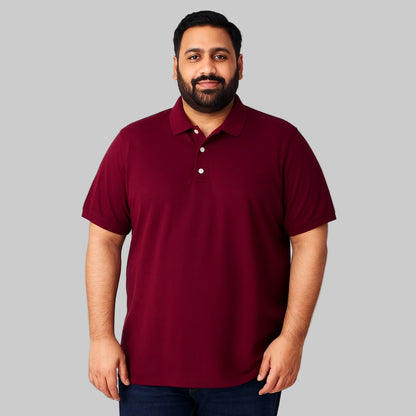 Plus-size Pakistani male model wearing dark magenta piqué polo shirt with chest pocket on a clean studio background.