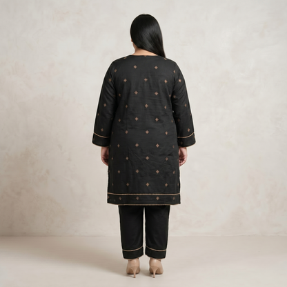Person wearing a black embroidered kurta with pants on a beige background