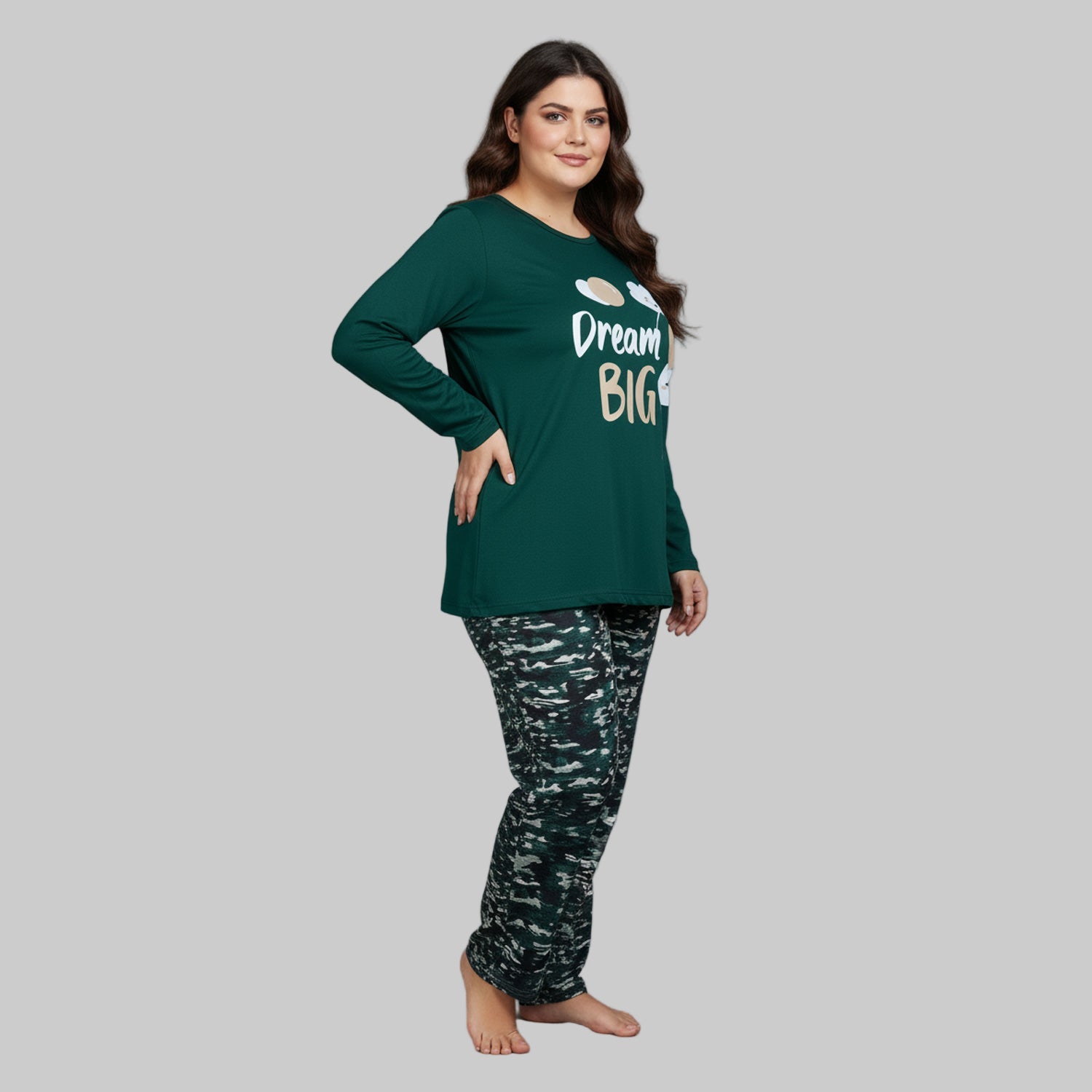 Plus-size woman wearing a forest green “Dream Big” long-sleeve pajama top with printed forest-pattern pants — cozy cotton-blend sleepwear set.