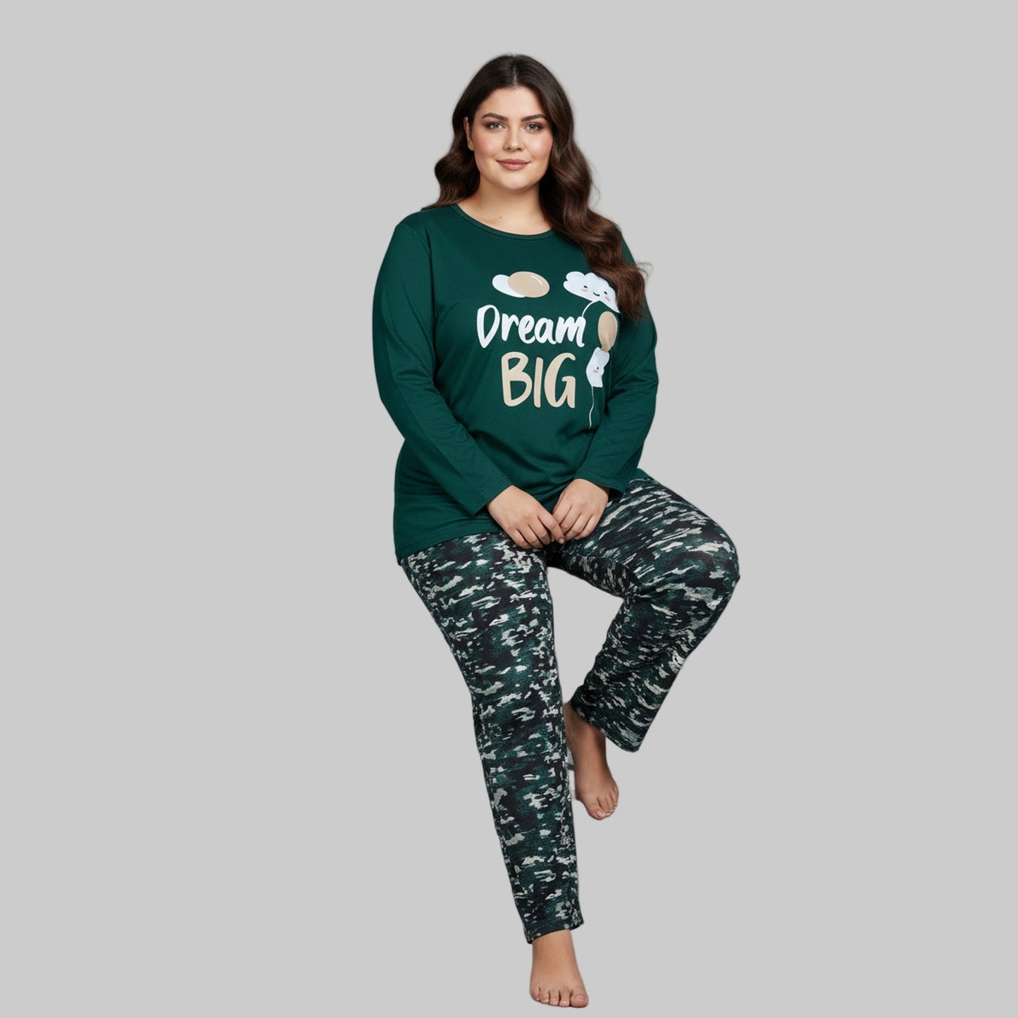 Plus-size woman wearing a forest green “Dream Big” long-sleeve pajama top with printed forest-pattern pants — cozy cotton-blend sleepwear set.