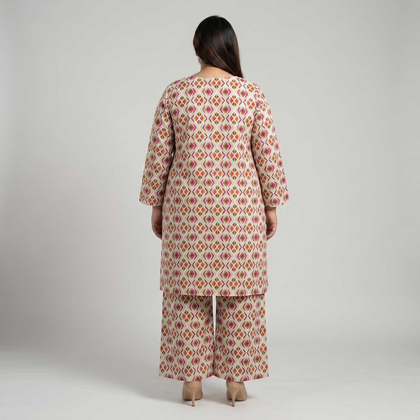 Woman wearing a patterned kurta with palazzo pants on a plain background