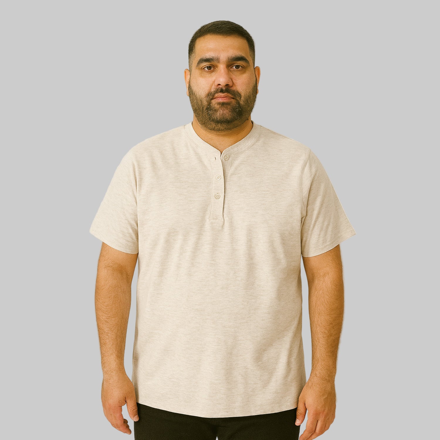 Plus-size Pakistani male model wearing heather oatmeal short-sleeve Henley shirt on a studio background, relaxed fit.