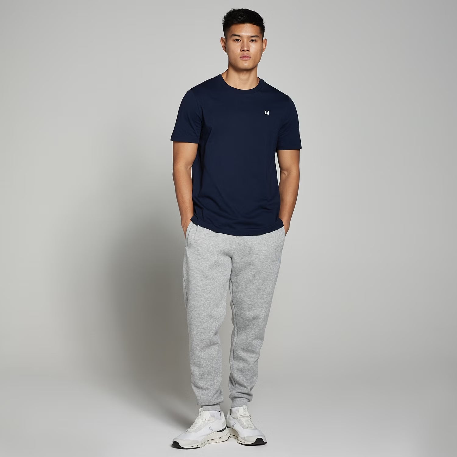  Heather grey fleece jogger pants with elastic waistband and ribbed ankle cuffs, worn by a model for casual everyday comfort.